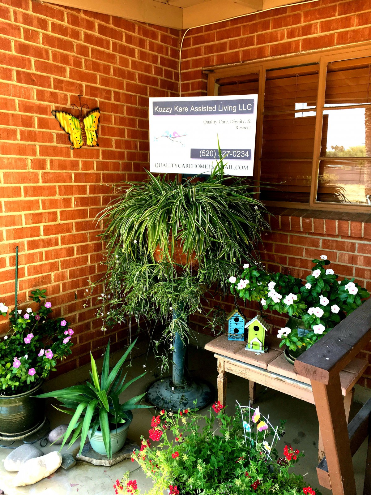 A cozy garden nook featuring a variety of potted plants, vibrant flowers, and charming decorations against a brick wall backdrop.