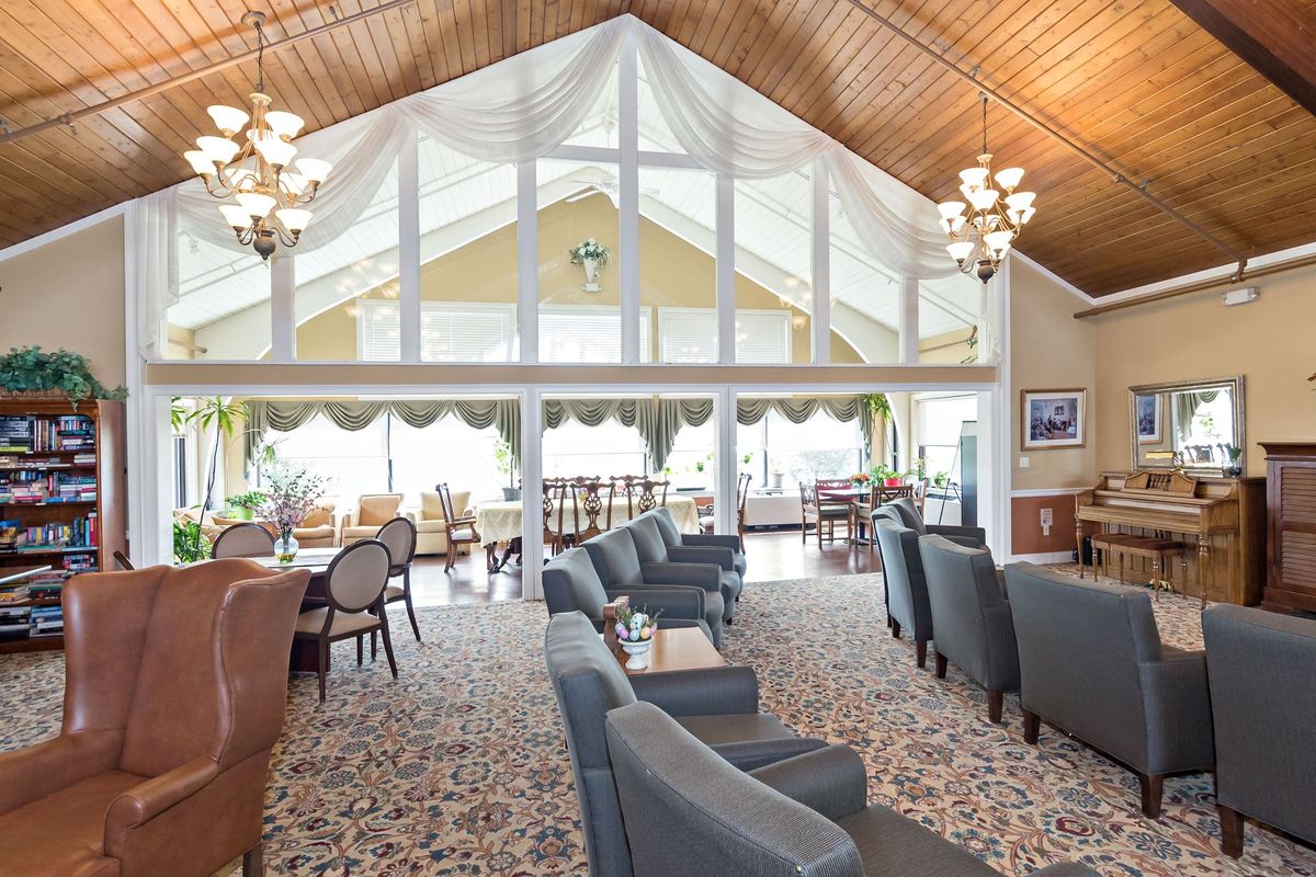 A spacious lounge with high ceilings, large windows, and elegant chandeliers, featuring comfortable seating arrangements.