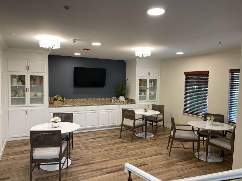 A modern indoor dining area with tables and chairs, featuring a television and stylish lighting.