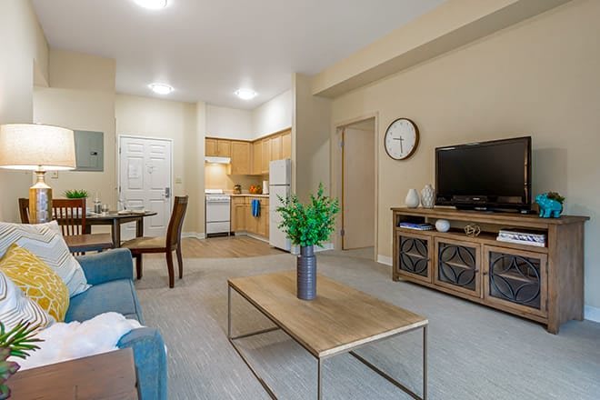 A cozy and modern apartment living area with a view of the kitchen, featuring stylish furniture and decor.