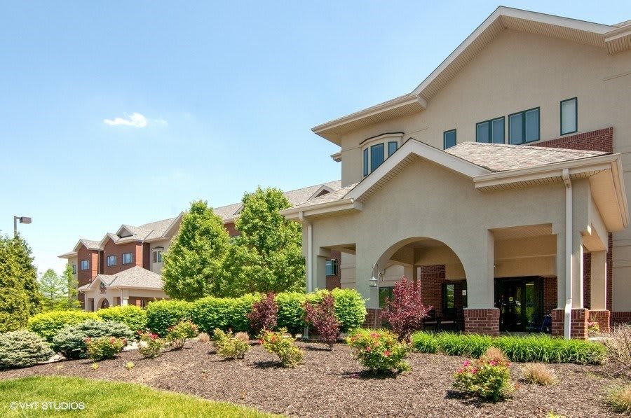 A suburban house with well-maintained landscaping under a clear blue sky.