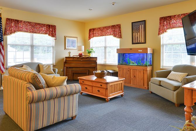 A cozy living room with a piano, aquarium, and comfortable seating.