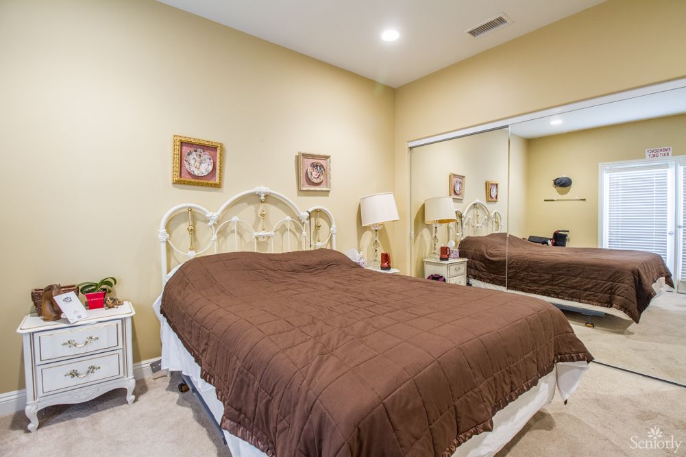 A cozy bedroom with a large mirror and soft lighting.