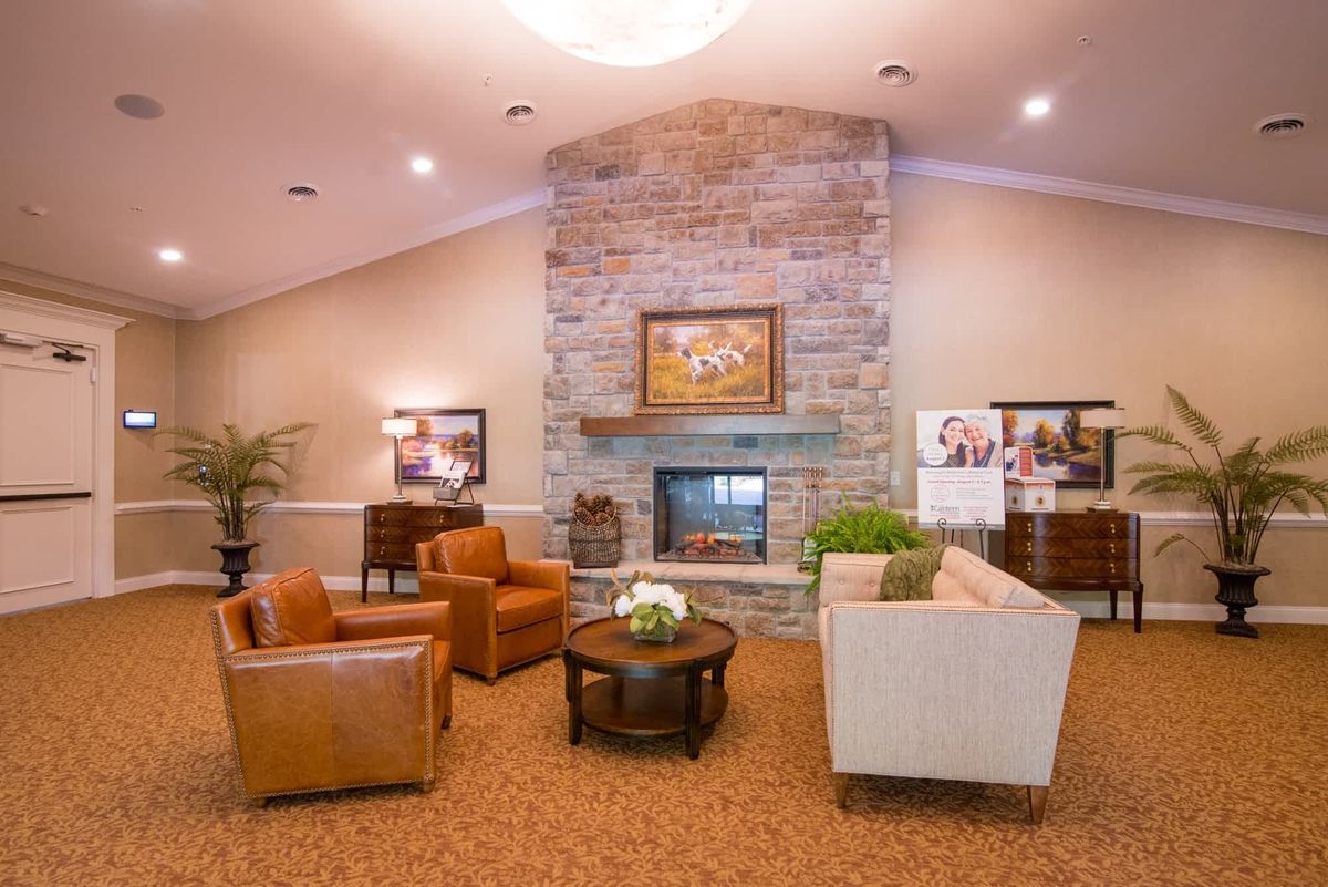 A cozy living room with a stone fireplace, leather armchairs, and a comfortable sofa.