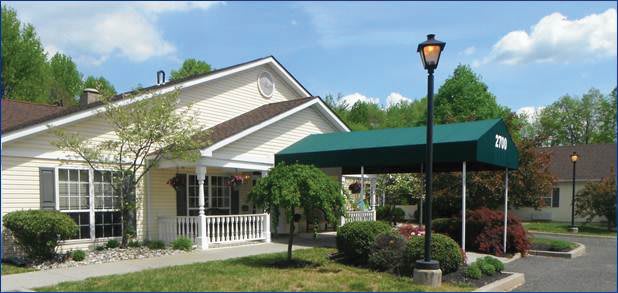 A quaint house with a green awning and surrounding garden.