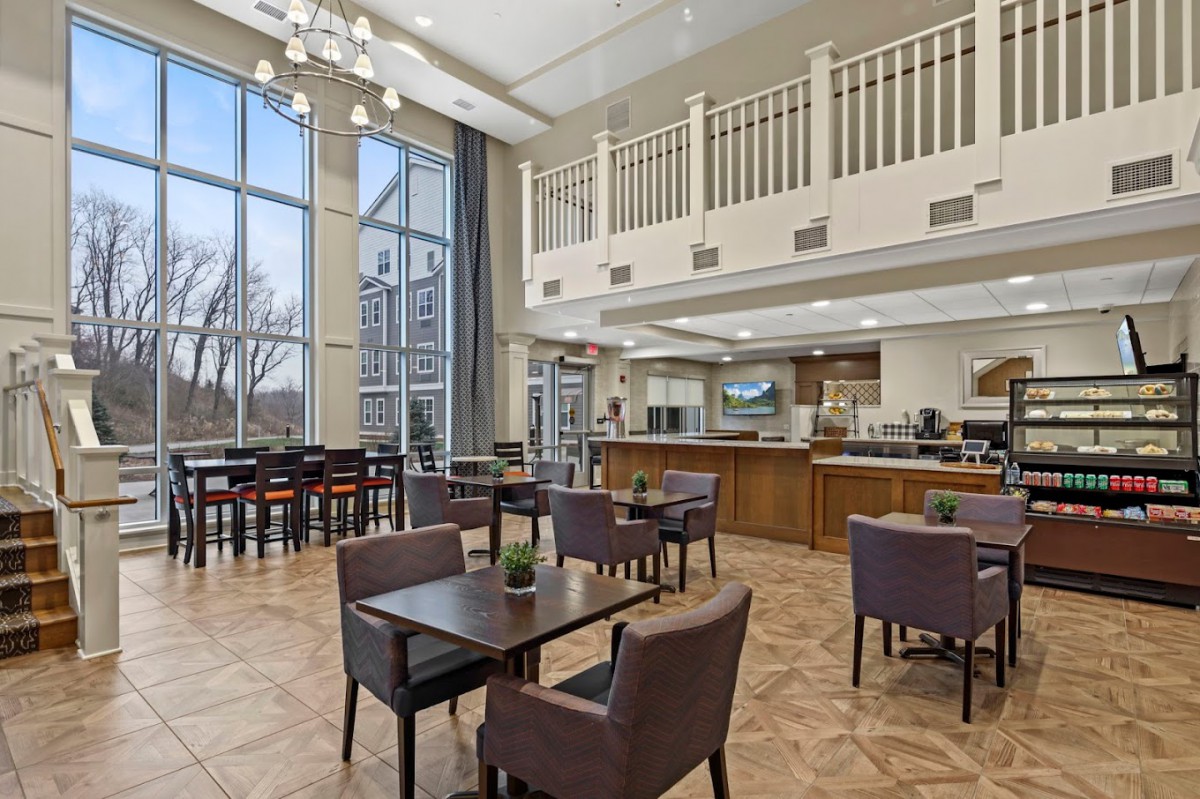 A modern cafe with a spacious dining area featuring high ceilings, large windows, and contemporary seating arrangements.
