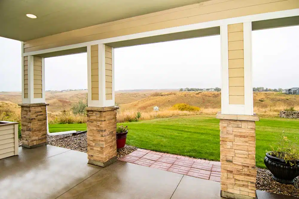 A covered patio overlooking a grassy landscape.