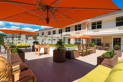 A sunny outdoor patio area with orange umbrellas and comfortable seating.