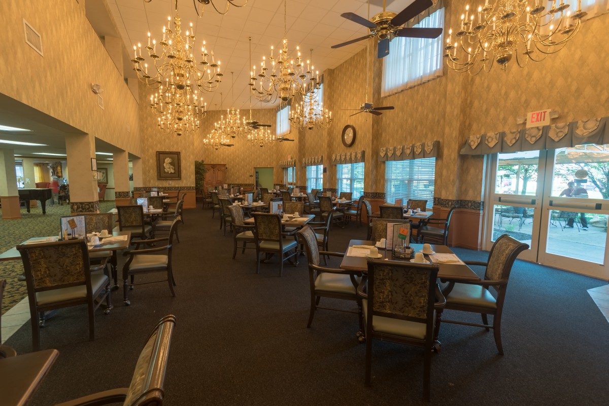 An elegant restaurant dining room featuring chandeliers and neatly arranged tables.
