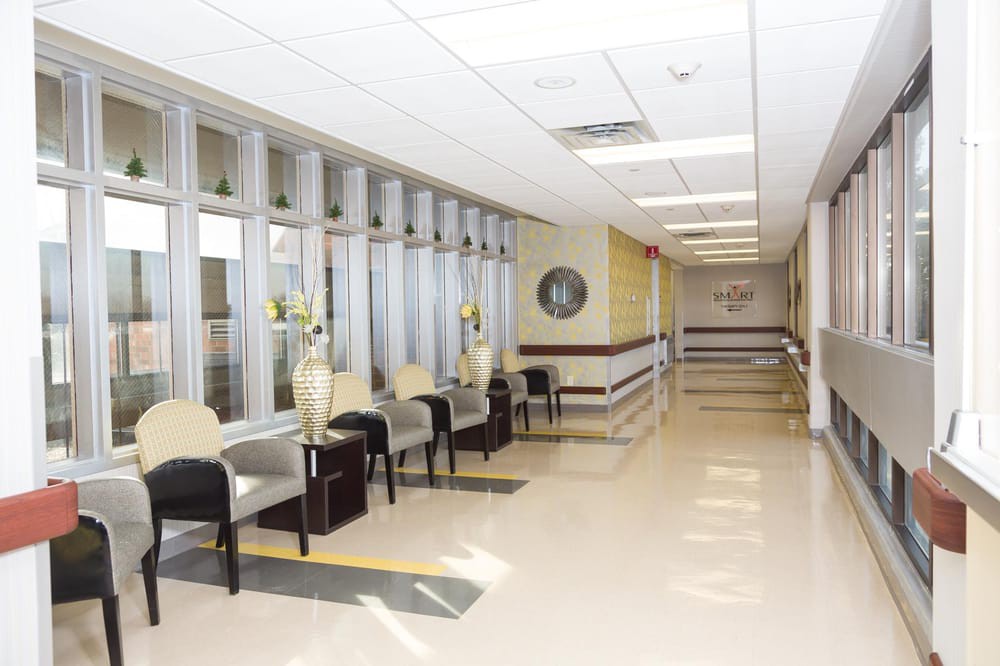 A bright hospital hallway with a waiting area featuring chairs and decorative elements.