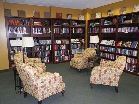 A cozy reading area in a library with comfortable armchairs and bookshelves filled with books.