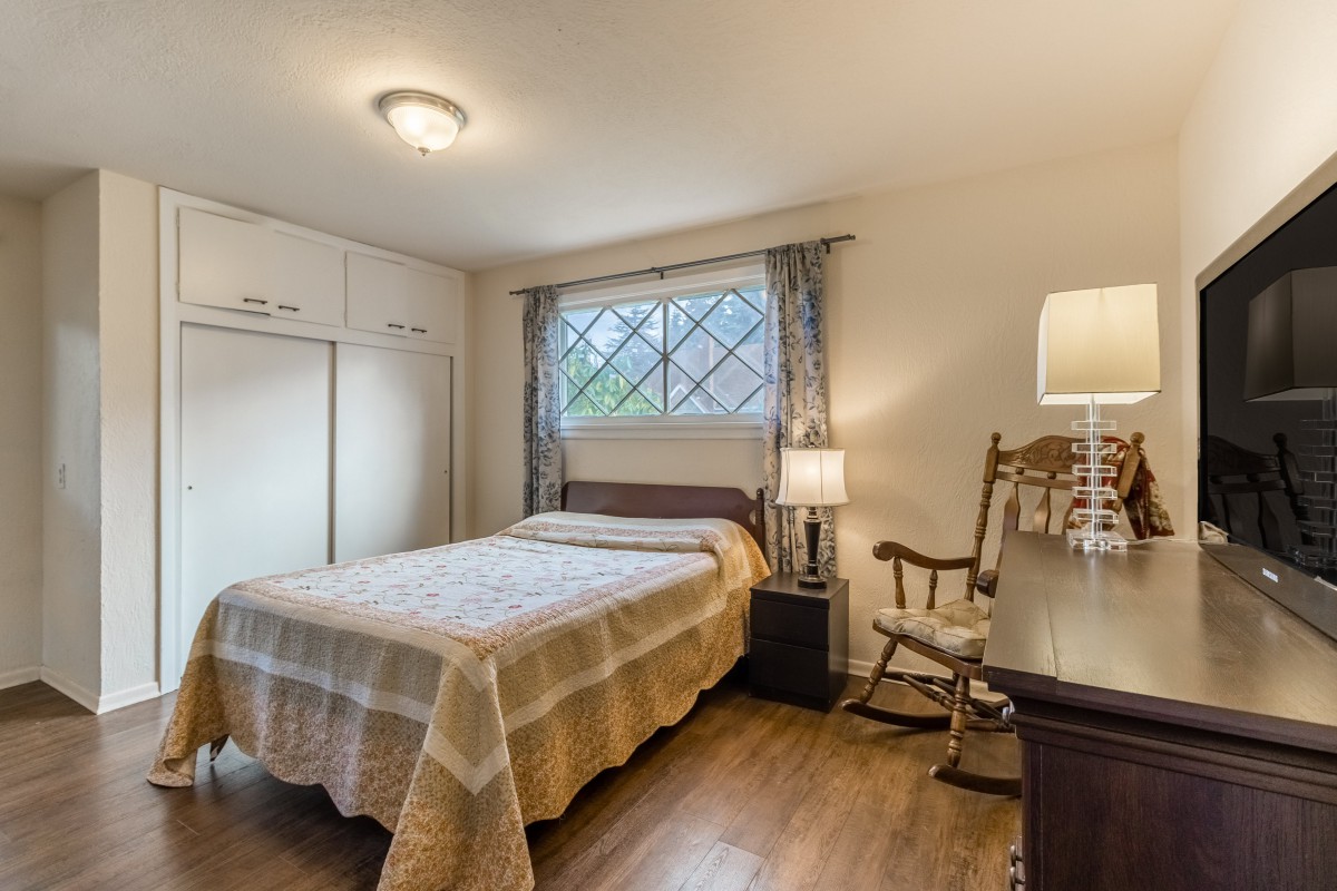 Cozy bedroom with a bed, rocking chair, and window letting in natural light.