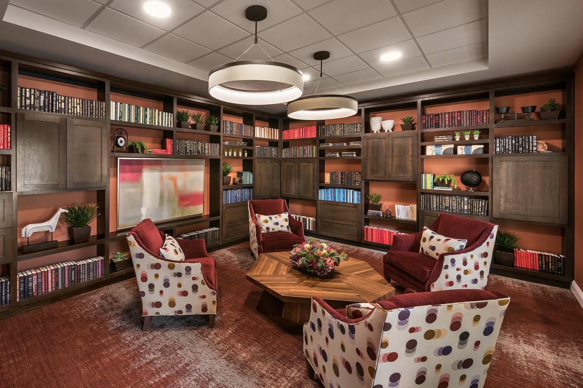 A cozy library with armchairs and wooden bookshelves filled with books.