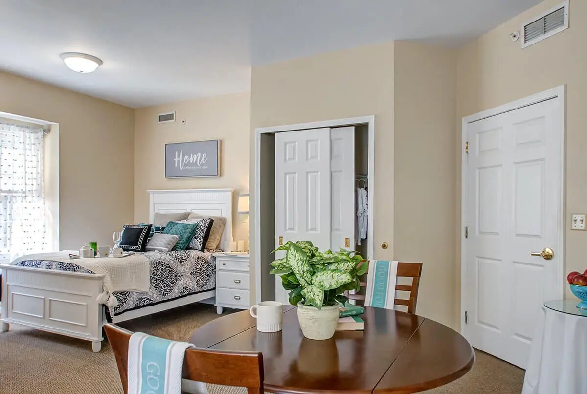 A cozy bedroom with a neatly made bed, small dining table, and stylish decor.