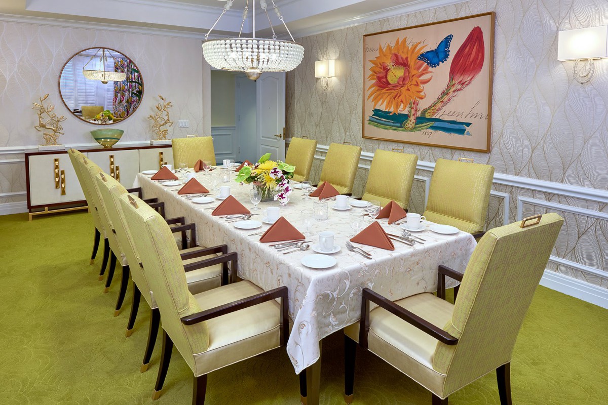 A formal dining room with an elegantly set table, featuring a chandelier and colorful artwork.