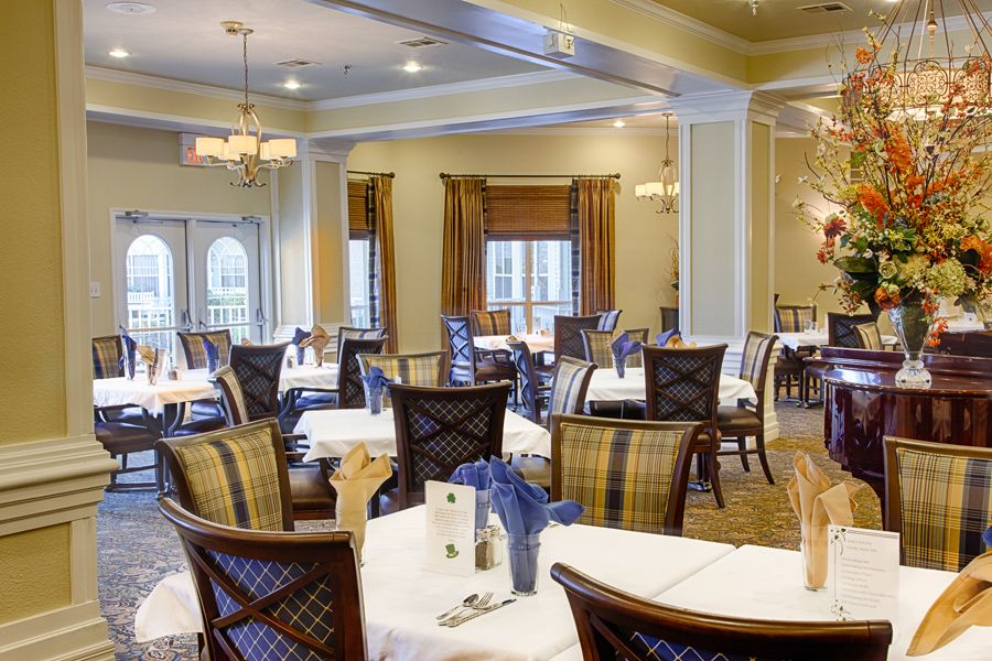 A formal dining room with elegantly set tables and chandeliers.