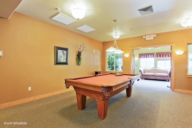 A spacious game room with a billiard table and comfortable seating.