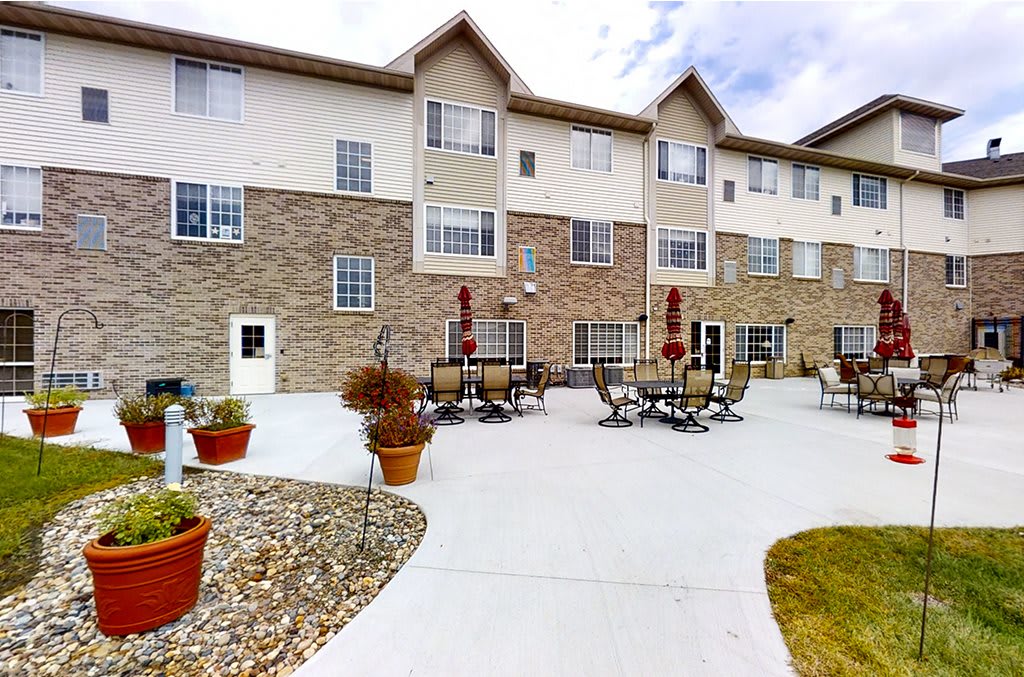 A residential building with an outdoor patio area featuring tables and chairs.