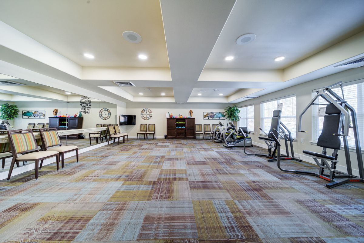 A spacious and modern gym with various exercise equipment and ample lighting.