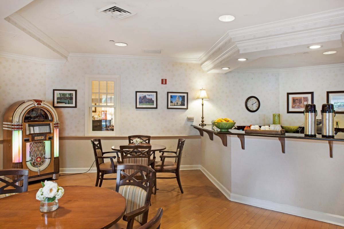 A cozy dining area with tables and chairs, adorned with artwork and gentle lighting.
