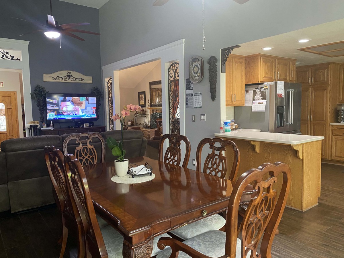 A cozy dining area with a wooden table and chairs, open to a living space and kitchen.