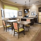 A modern kitchen and dining area with tables and chairs, featuring stylish lighting and a large window for natural light.