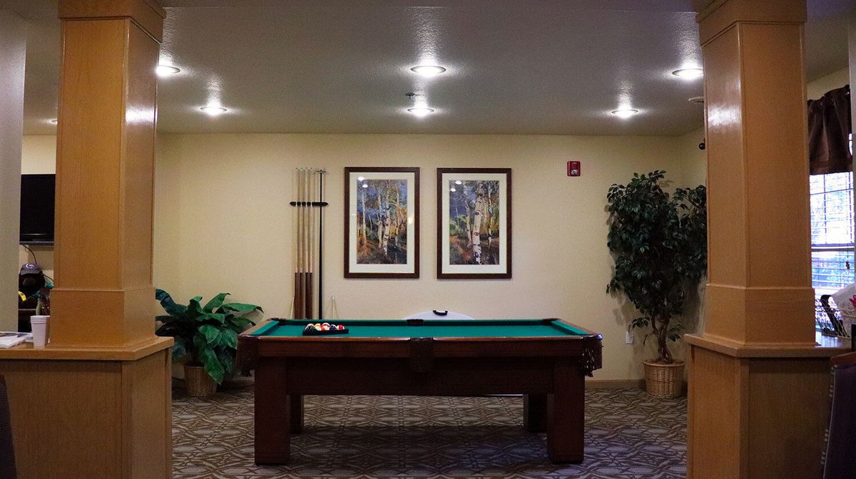A cozy billiard room featuring a pool table, artwork, and soft lighting.