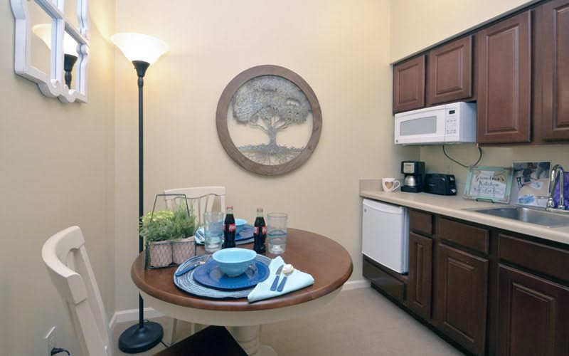 A cozy kitchen with a small dining table set for two, featuring modern appliances and decor.