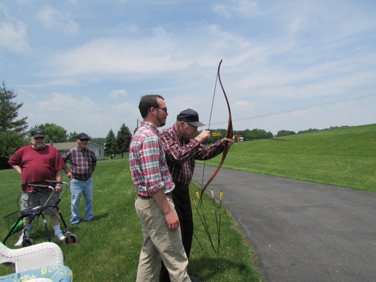 A group of people practicing archery outdoors on a sunny day.