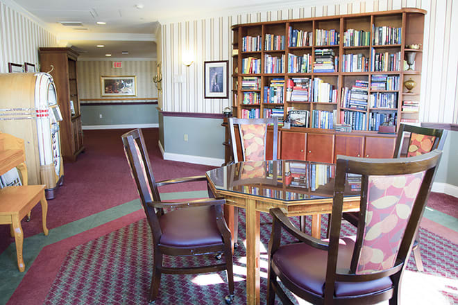 A cozy library reading area with a bookshelf and table with chairs.