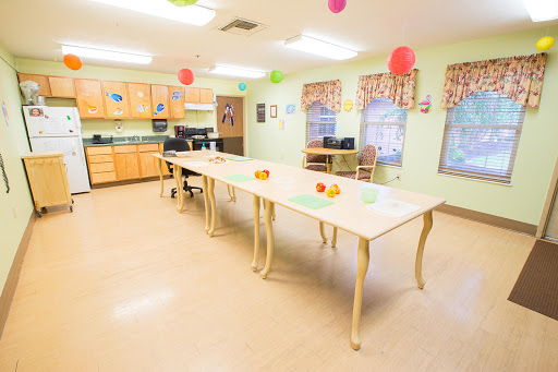 A brightly lit kitchen area with a long dining table set up for activities, adorned with colorful decorations.