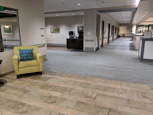 A spacious and modern lobby area featuring a green couch, with a well-lit hallway leading to various rooms.