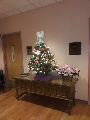 A beautifully decorated Christmas tree with lights, standing on a table in an indoor setting.