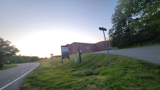 A tranquil scene of a building at sunset, surrounded by lush grass and directional signs.