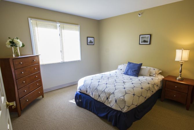 A cozy bedroom with a bed, wooden dresser, and window.