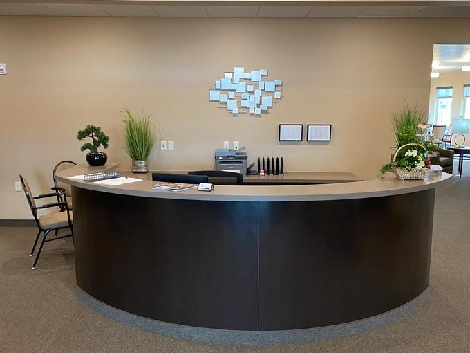 A modern office reception desk with plants and wall decor.