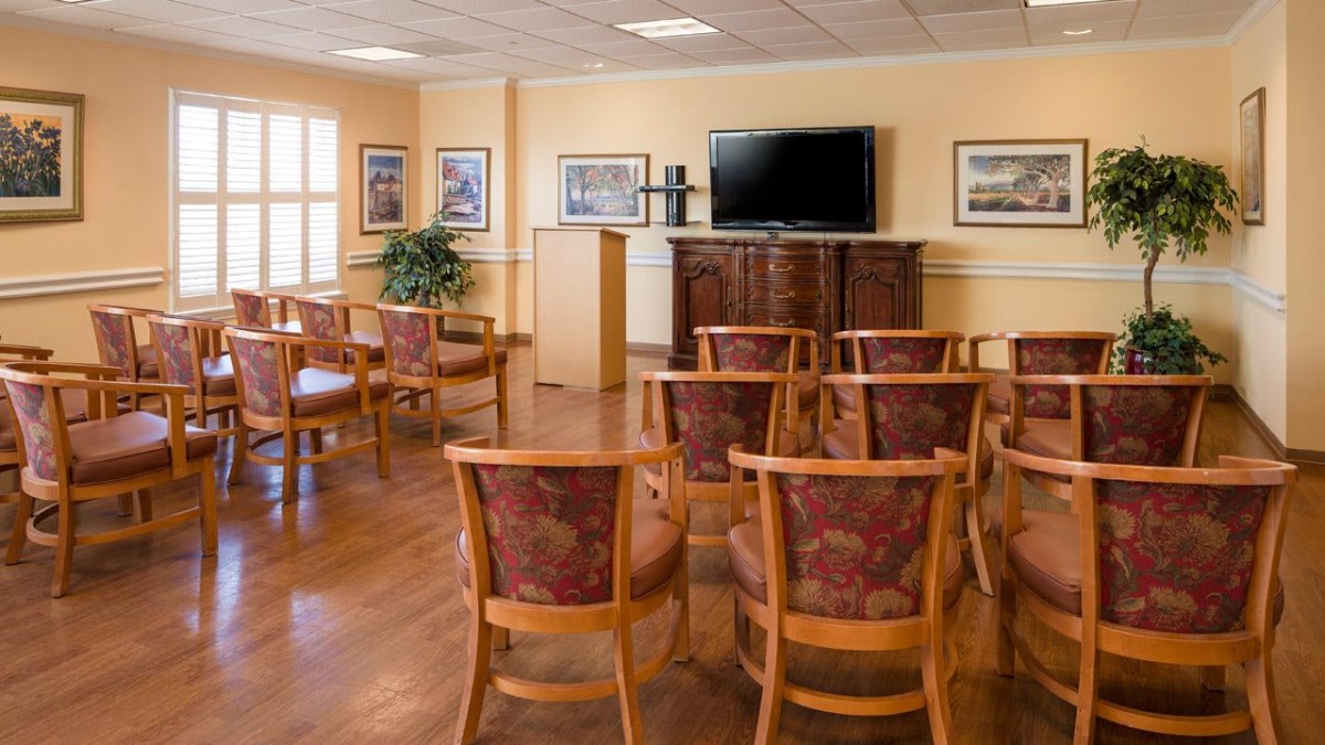 A well-organized meeting room with rows of chairs facing a large television screen.