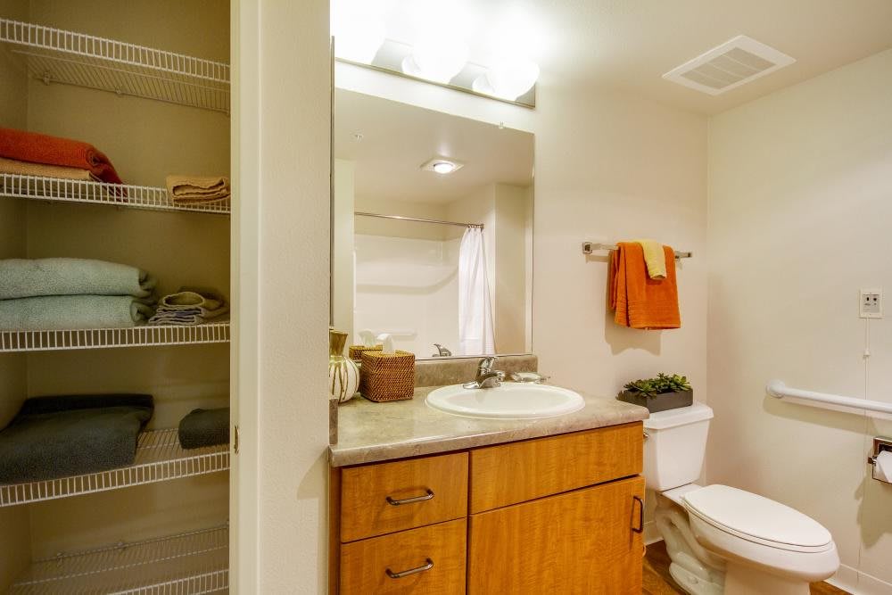 A clean and well-organized bathroom with a wooden cabinet, sink, mirror, and neatly arranged towels.