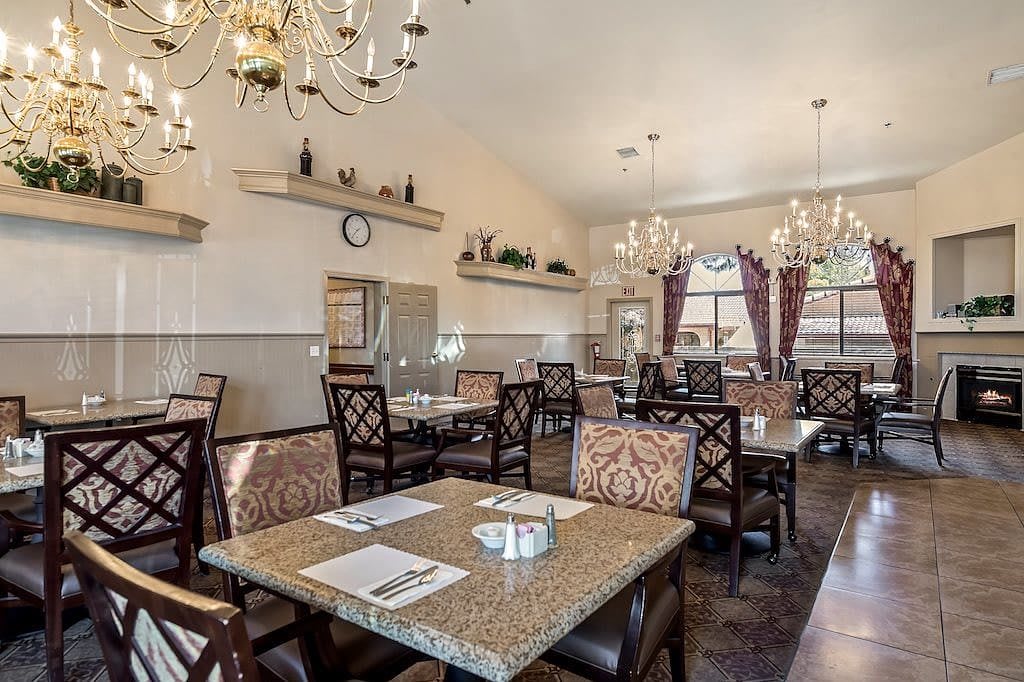 Elegant dining area with chandeliers and neatly arranged tables and chairs.