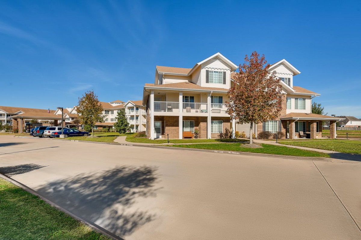 A suburban apartment complex on a sunny day with trees lining the street.