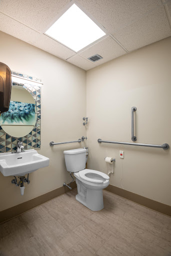 A modern bathroom equipped with accessibility features, including a sink, toilet, and handrails.