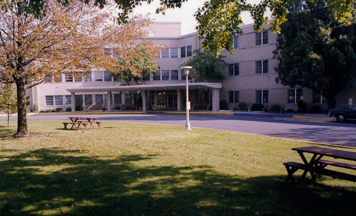 A view of a modern building surrounded by green grass and trees.