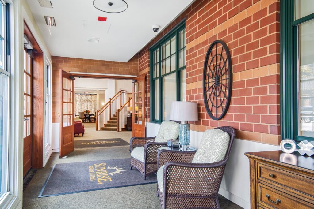 A cozy hallway with wicker chairs against a brick wall and decorative elements.