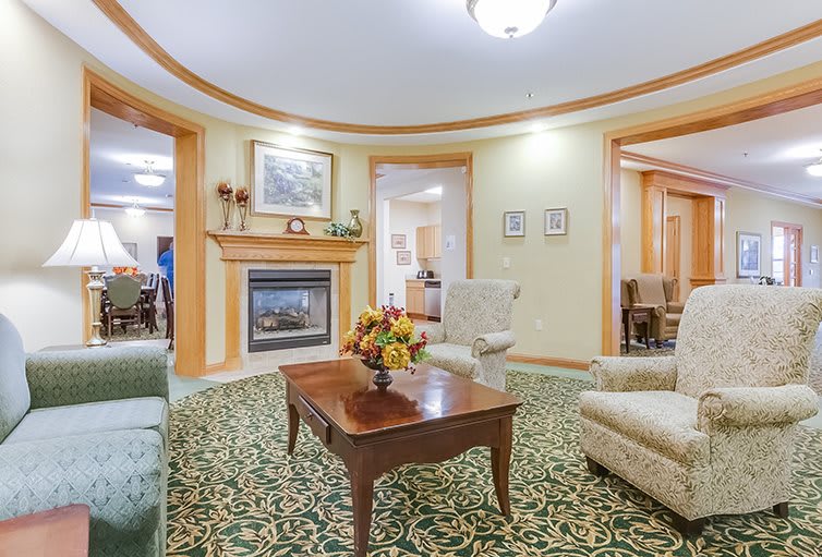 A cozy living room with a fireplace, plush seating, and a decorative carpet.