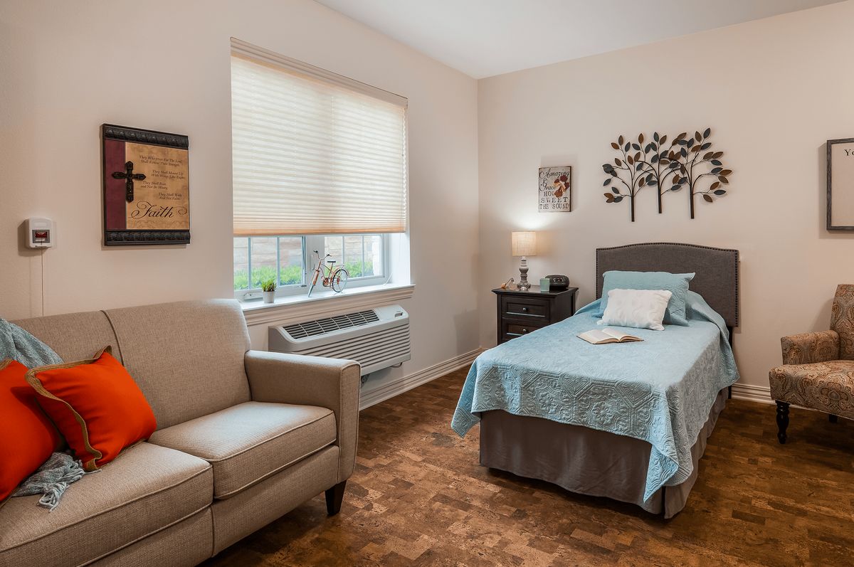 A cozy bedroom with a single bed, armchair, and stylish wall art.