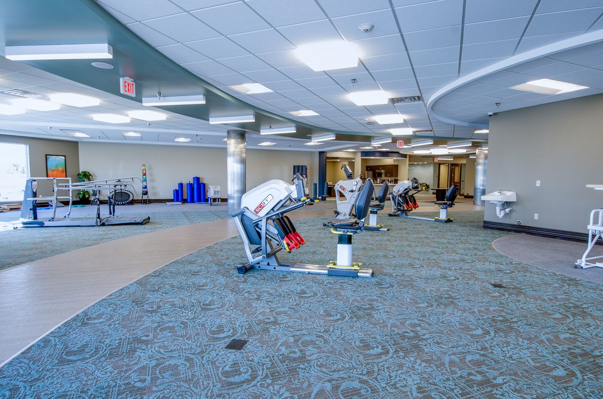 A spacious gym with various exercise equipment and ample lighting.