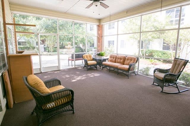 A spacious sunroom with comfortable seating and large glass windows.