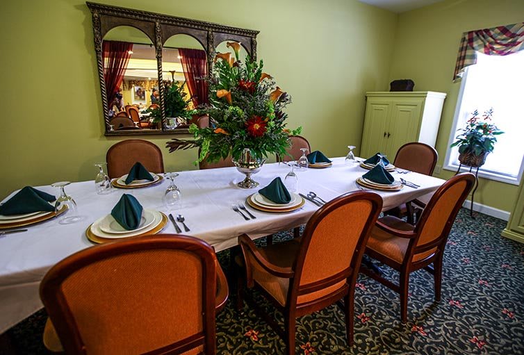 A formal dining room with an elegantly set table and floral centerpiece.