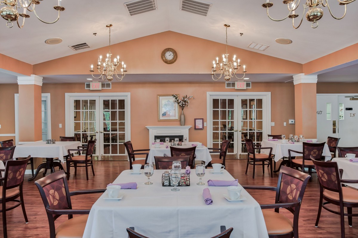An elegant dining room with neatly arranged tables and chandeliers hanging from the ceiling.