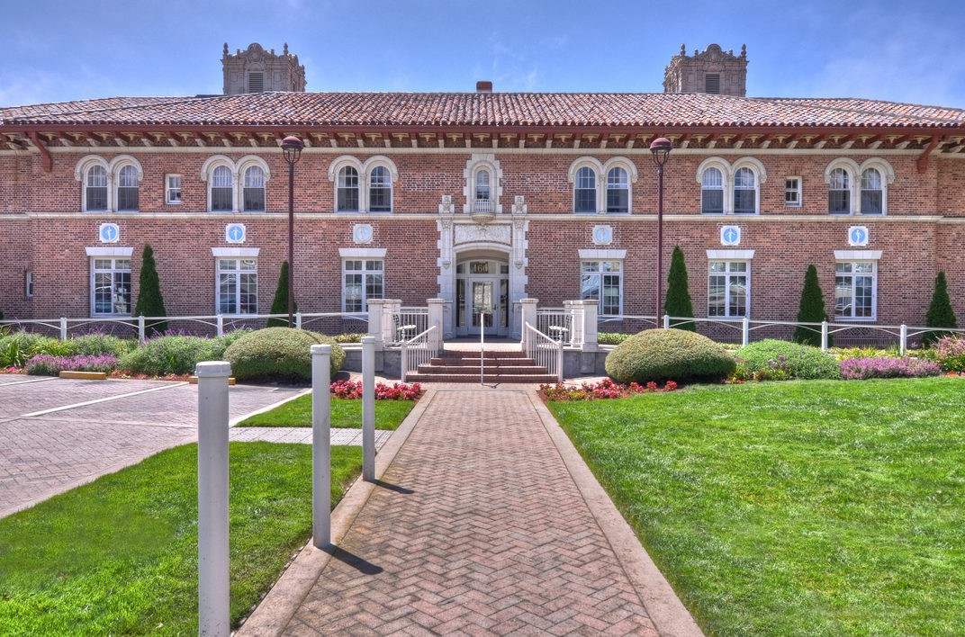 A historic brick building with a landscaped pathway leading to its grand entrance.